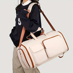 Person holding a beige duffel bag with brown accents on a light gray background