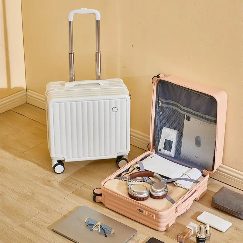White suitcase and open pink suitcase with travel items on a wooden floor.