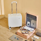 White suitcase and open pink suitcase with travel items on a wooden floor.