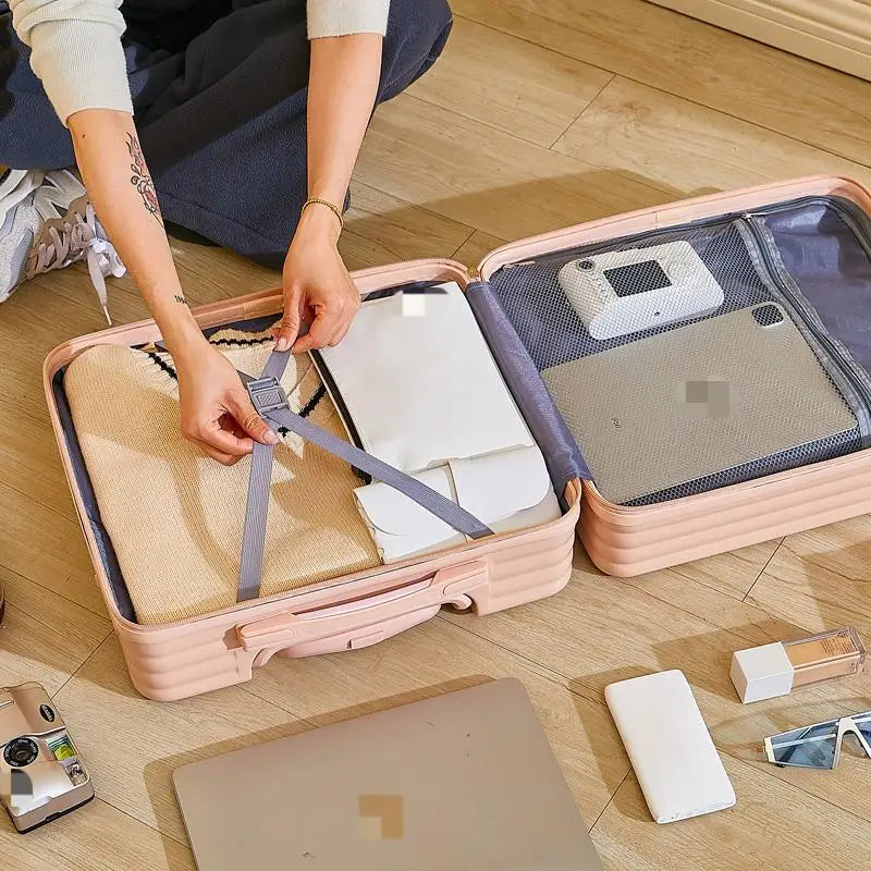 Person packing items into a suitcase on a wooden floor