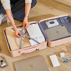 Person packing items into a suitcase on a wooden floor
