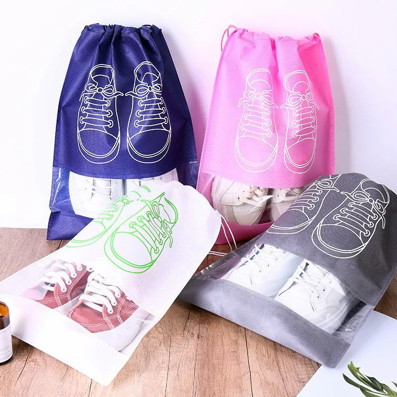 Set of shoe bags in blue, pink, green, and gray with shoe illustrations on a wooden surface.