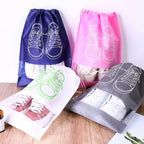 Set of shoe bags in blue, pink, green, and gray with shoe illustrations on a wooden surface.