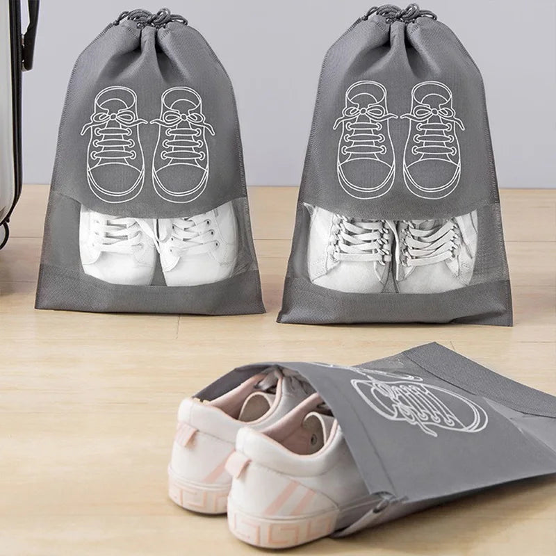 Gray shoe bags with white sneakers inside on a wooden surface.