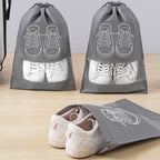 Gray shoe bags with white sneakers inside on a wooden surface.