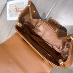 Brown leather handbag on a wooden surface with a blurred background