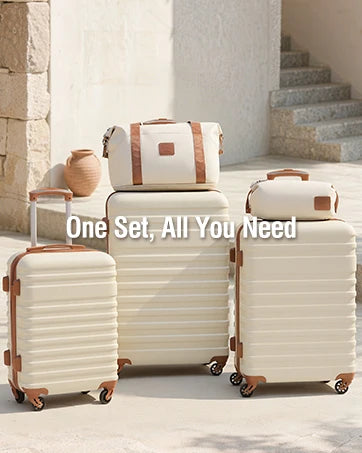 Set of cream-colored suitcases with brown handles and wheels on a stone pathway.