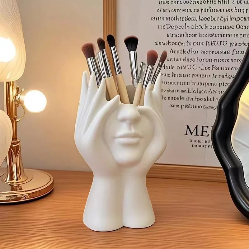 White hand-shaped brush holder with makeup brushes on a wooden surface.